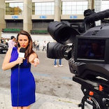 Semra posing for the camera while holding a RealMadrid TV microphone and reporting outside of the Santiago Bernabéu